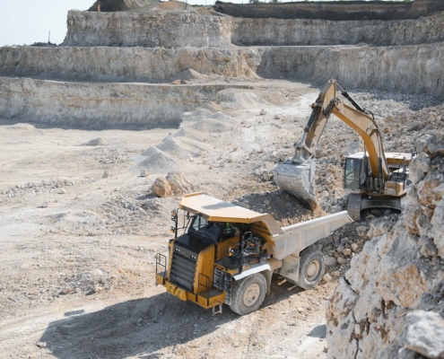 Heavy Mining Truck And Excavator, Close Up, Against The Background Of The Panorama Of A Limestone Quarry