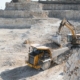 Heavy Mining Truck And Excavator, Close Up, Against The Background Of The Panorama Of A Limestone Quarry